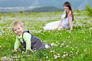 Tranh meẹ và bé ngồi trên thảm cỏ
